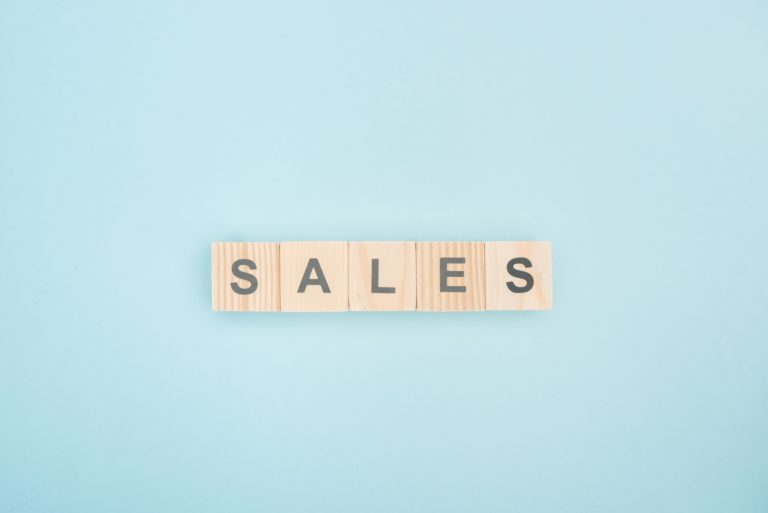 top view of sales lettering made of wooden cubes on blue background